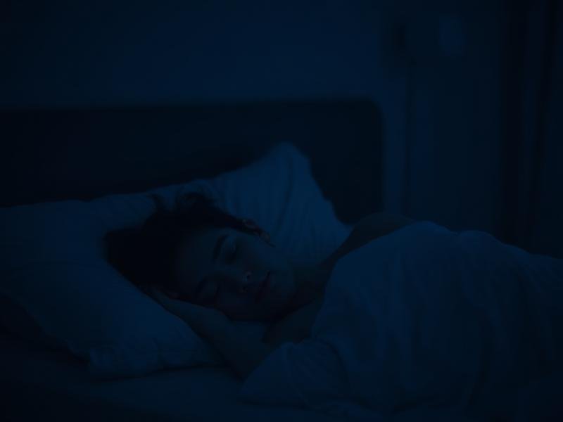 Person sleeping peacefully in a dark, calm bedroom